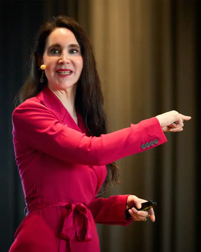 Kommunikationsexpertin bei Vortrag, Anabel Ternés, auf Bühne, in rotem Businessanzug, spricht leidenschaftlich über Medienstrategie, Public Relations und Moderation, inspirierend, professionell, engagiert.